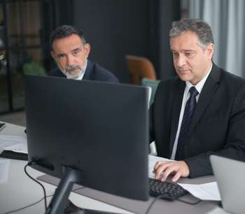 Two business men sitting in front of a computer