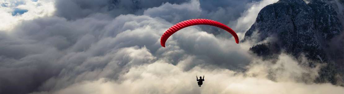 Person parasailing in front of a mountain